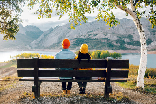 Couple sitting on bench near mountains