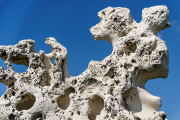 An old stone of complex shape against the background of a blue sky