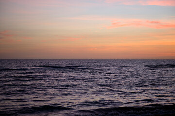 Fototapeta na wymiar Dramatic red ocean waves at sunset with soft evening sea dark water
