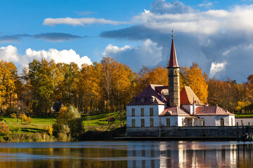 Priory Palace on the shore of the lake in Gatchina near St. Petersburg in the autumn afternoon, the castle against the background of the autumn forest

