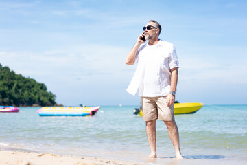 Man  on the beach , young man taking a walk on the beach in summer. Man using the smartphone at the seaside, Senior man using smart phone while standing at beach 