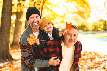 Happy two man couple with adopted child on autumn season