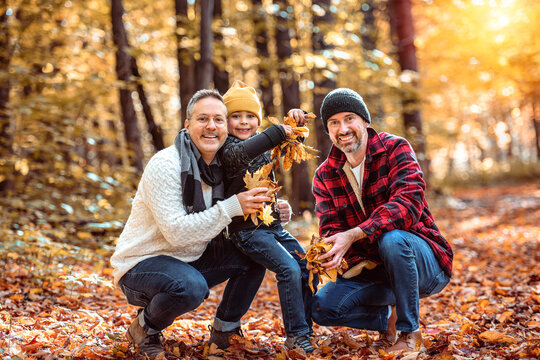 Happy two man couple with adopted child on autumn season