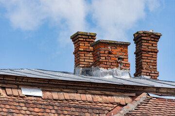 Three smoking chimneys made of bricks that needs restoration with a seagull in one of them on a...