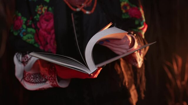 Woman holding Kobzar - poetry book collection of Taras Shevchenko - poet, bard in Ukrainian culture. Lady in traditional costume turns pages.