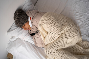 Freezen man sleep in bedroom. Cold home in winter. Heating season. Cold young man covered with...