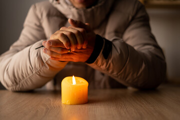 Shutdown of heating and electricity. A man dressed in a warm winter jacket sits at home at a table...