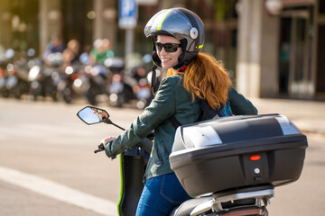 Red-haired woman riding a motorcycle on a city street