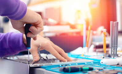 Fototapeta premium Worker technician repairing broken laptop notebook with screwdriver, keyboard replacement for modern computer