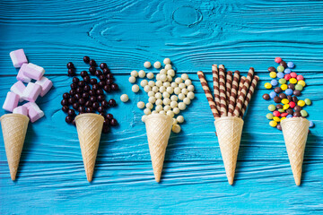 Ice cream cones with colorful candies, cookies, and chocolate balls