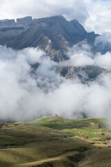 Montain hut with lush meadows in the French Pyranees surrounded by clouds with the Breche de Roland in the background