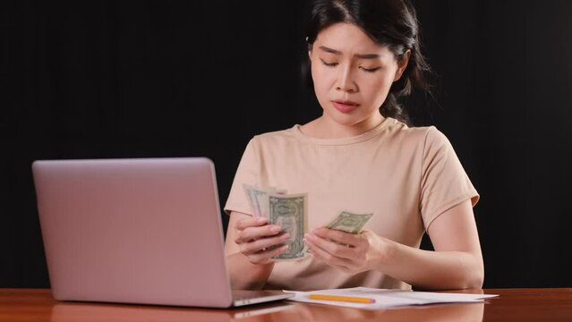 Asina woman counting her money while trying to pay her bills.