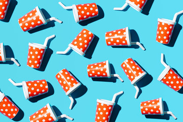 Cute plastic party cups with straws, creative fast food inspired pattern against bright blue background. 