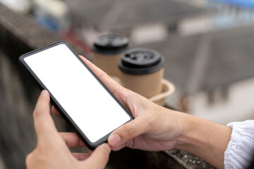 Young woman hold smartphone with white screen while sitting on a couch. Outdoors woman using a phone in the city