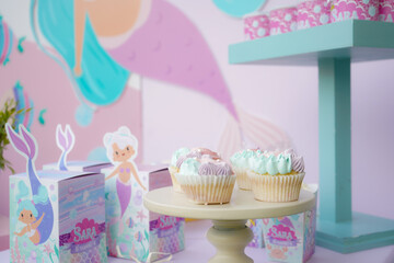 Candy table: cupcakes, cookies, and desserts; themed decoration for mermaid children's birthday party.                               