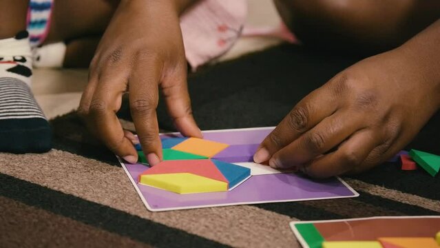 Young Black children, Black girls, Black boy, and Black infant baby playing with building blocks, toys, and train sets