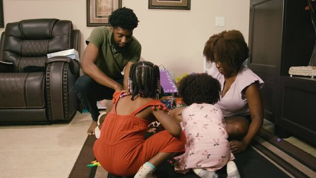 Young Black children, Black girls, Black boy, and Black infant baby playing with building blocks, toys, and train sets