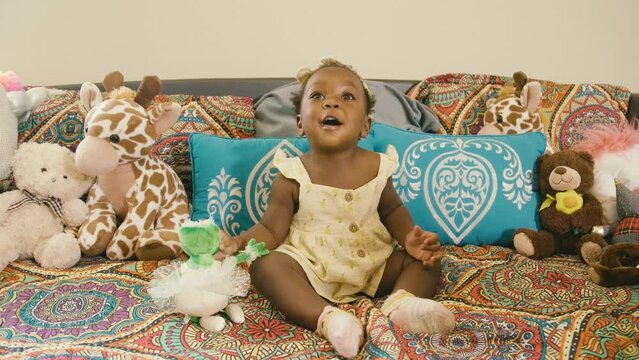 Young Black infant baby girl playing with toys and stuffed animals in playroom at home and school
