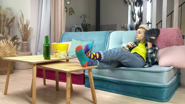 Carefree Woman Relaxing, Watching TV, Eating Snacks, Catching Ball With Baseball Glove But Failure While Sitting On Sofa Indoors. Young Female Fan Preparing To Cheer Baseball Game At Home