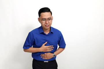 Young asian man standing and suffering from stomachache while holding his tummy. stomach acid concept