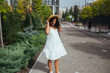Beautiful in a white dress poses on the street