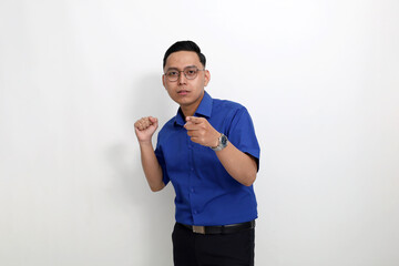 Unsatisfied young asian man standing with clenched hand while pointing at the camera. Isolated on white background