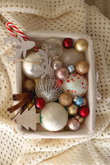 Basket with various Christmas ornaments and knitted blanket. Top view.