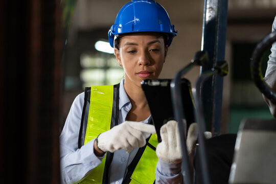 Female engineer work with digital tablet at the industry factory area. Woman technician wear safety helmet and uniform working in the factory