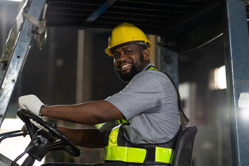 Happy African American male engineer driving and operating on forklift truck in the industry...