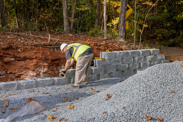 As installation process contractor worked to construct large block retaining wall on construction site