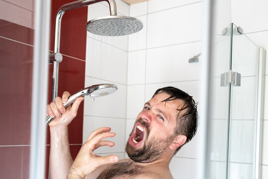European man singing loudly in the shower using a watering can as a microphone.