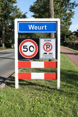 Place name sign for the village of Weurt, the Netherlands (also speed limit of 50 km per hour, and...