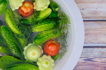Prepare pickles by washing cucumbers, squashes, and tomatoes.