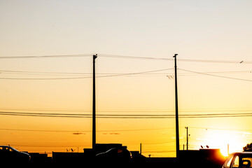 Fototapeta na wymiar Silhouette of streetlights, houses and cars, during the sunset in the Brazilian city.