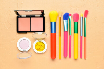 Set of makeup brushes, blush and eyeshadows on color background