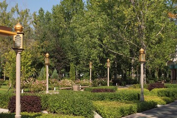 Trees and flowers in city park with Indian style lantern. Pedestrian zone for walking. Urban planning, public space concept. Town recreation area. Architecture design comfortable garden. Footpath way