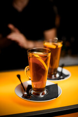 Close-up view of transparent cups on saucer with tea and lemon on bar counter