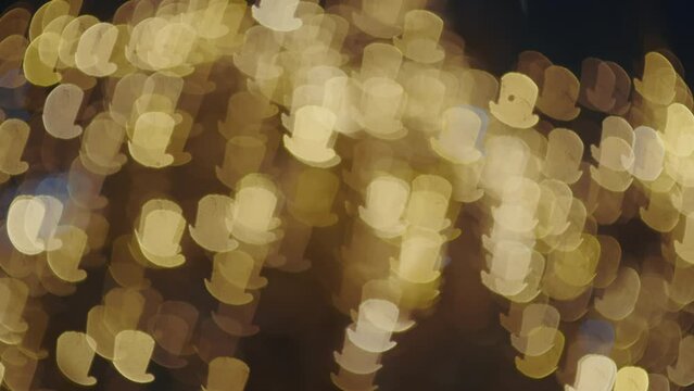 Textured blur shot of outside lights in shape of cylinder hat. City lights bokeh dyring snow on holidays.