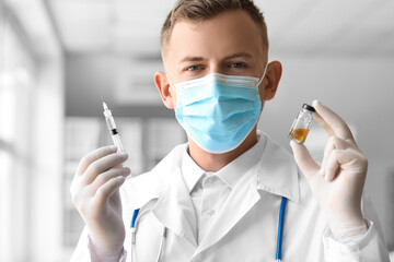 Male doctor in medical mask with syringe and ampule at hospital, closeup