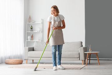 Young housewife mopping floor at home