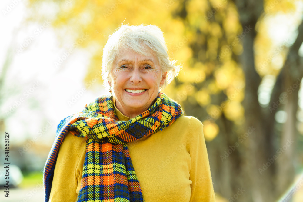 Wall mural happy elderly senior woman in an autumn park.