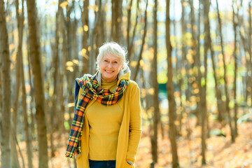 Happy elderly senior woman in an autumn park.