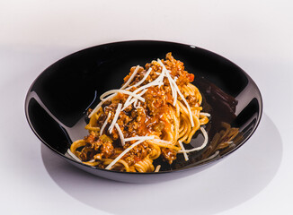 Pasta pappardelle with beef ragout sauce in black bowl. Grey background. Close up. Top view.