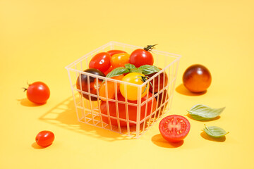 Basket with fresh ripe tomatoes on color background