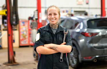 Handsome mechanic job woman in uniform working on car