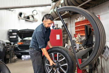 Obraz na płótnie Canvas Nice and cool mechanic changing car tire at work