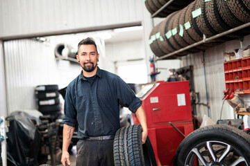 Fototapeta na wymiar Nice and cool mechanic changing car tire at work