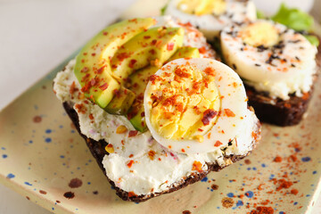 Tasty toasts with boiled eggs and board on white background, closeup
