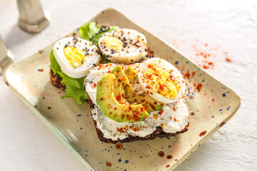 Tasty toasts with boiled eggs and board on white background, closeup