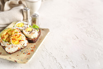 Tasty toasts with boiled eggs and board on white background, closeup